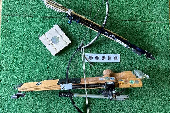 zwei Fabrikate einer 10m Armbrust, mit Pfeil/Bolzen, Scheibenholz mit Bleikern und Streifenscheibe. Das eine Fabrikat (oben) hat einen eingebauten Spannhebel.